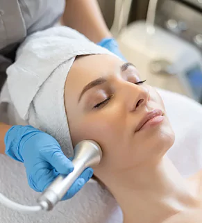 A woman receiving a facial treatment using a specialized machine in a serene spa environment.