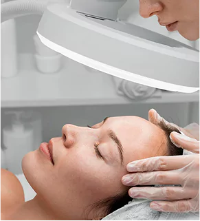 A woman receiving a facial treatment at a salon, relaxing on a treatment bed with soothing lighting around her.