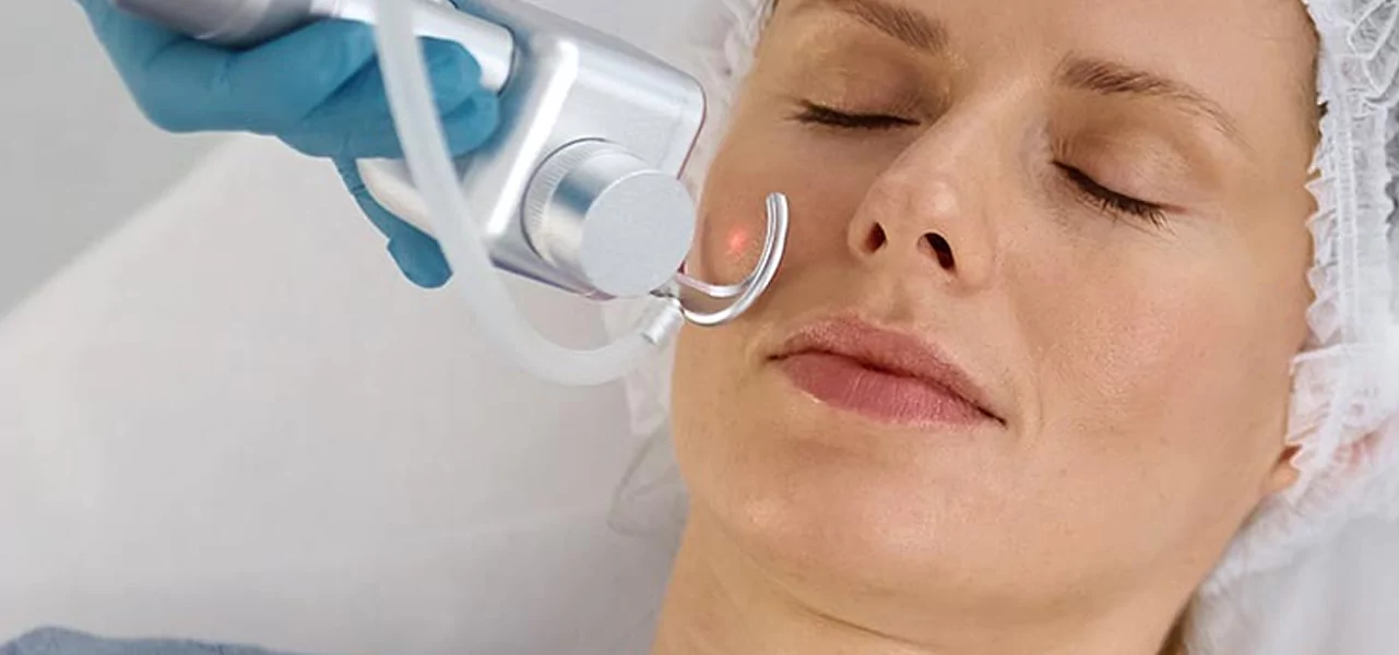A woman receiving a skin laser treatment using a specialized machine in a serene spa environment.